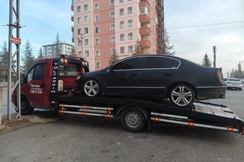 Yüksek apartman blokları önünde siyah sedan otomobili taşıyan Emin Oto Kurtarma çekicisi