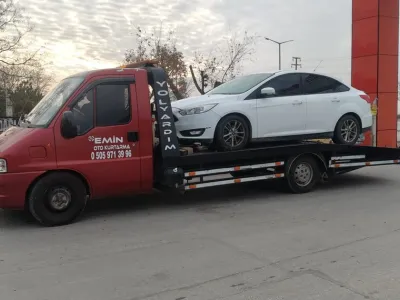 Karadağlı yön tabelası yanında beyaz sedan otomobili taşıyan Emin Oto Kurtarma çekicisi