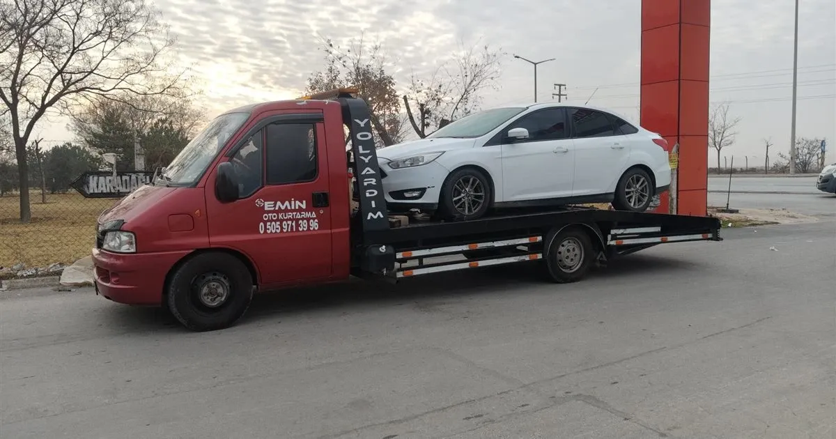 Karadağlı yön tabelası yanında beyaz sedan otomobili taşıyan Emin Oto Kurtarma çekicisi