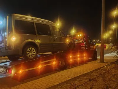 Gece sokak lambaları altında yol kenarında gri hafif ticari aracı taşıyan Emin Oto Kurtarma çekicisi