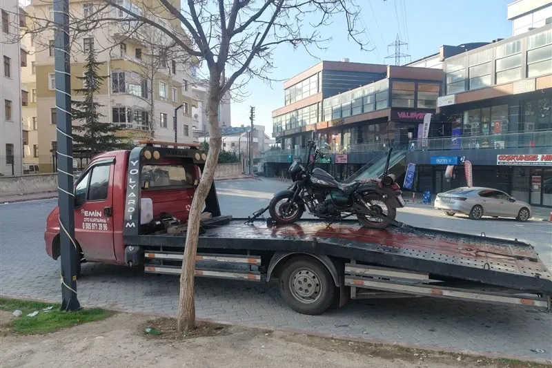 Şehir içinde iş merkezleri önündeki caddede siyah motosiklet taşıyan Emin Oto Kurtarma çekicisi