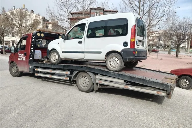 Yaprak dökmüş ağaçların olduğu caddede beyaz hafif ticari araç yüklü Emin Oto Kurtarma çekicisi