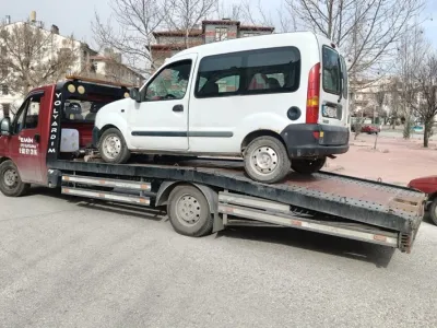 Yaprak dökmüş ağaçların olduğu caddede beyaz hafif ticari araç yüklü Emin Oto Kurtarma çekicisi
