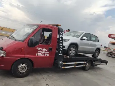 Yol kenarındaki akaryakıt istasyonunda gümüş gri SUV yüklü Emin Oto Kurtarma çekicisi, arkada tır